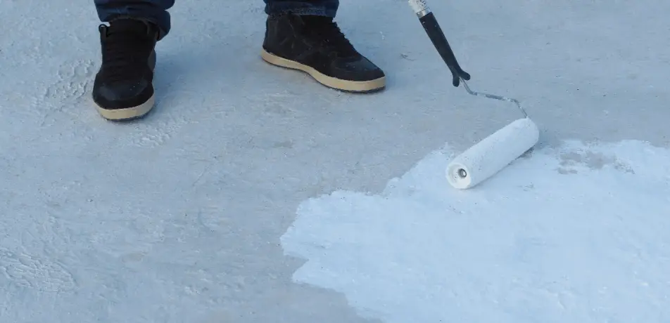 Roofer applying white coating on Tucson flat roof