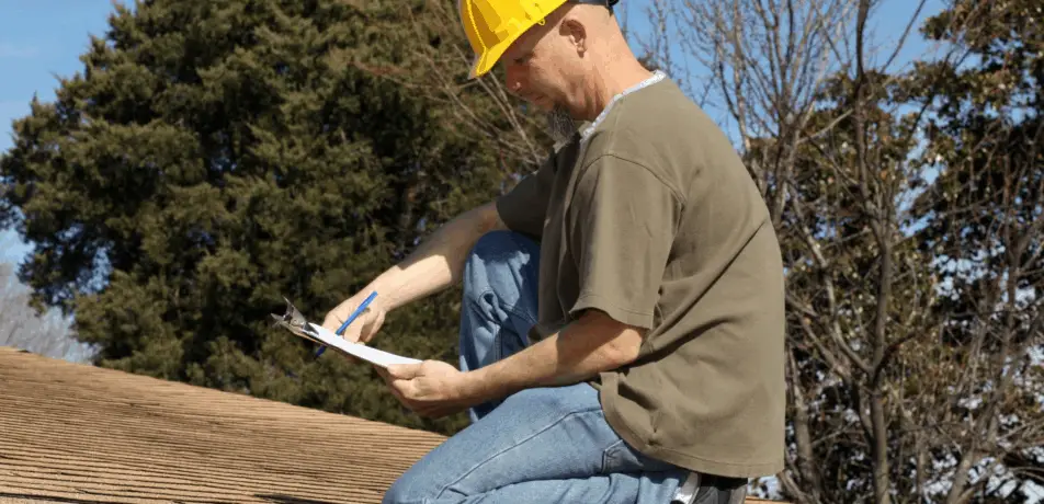 Contractor with clipboard inspecting roof in Tucson