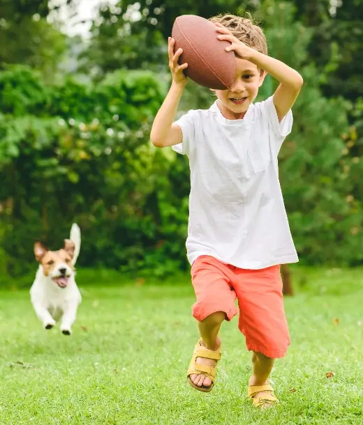 Child playing outdoors with a football
