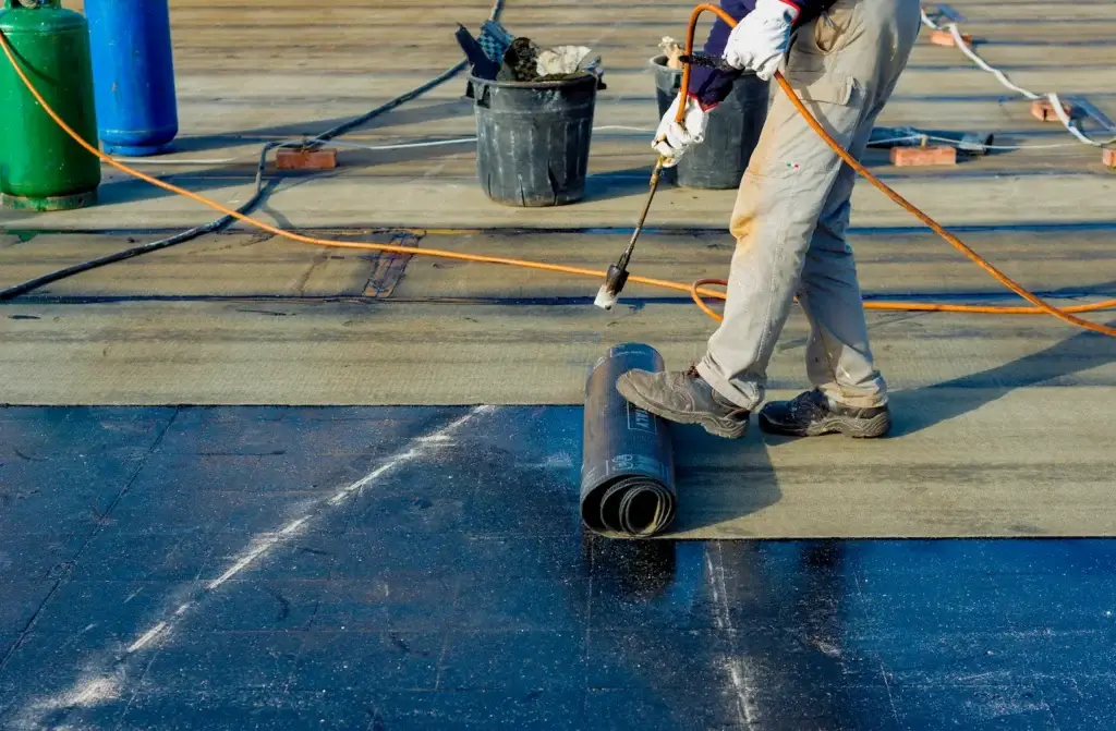 Crew rolling out flat roof membrane in Tucson